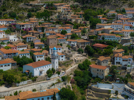 Aerial view of the historic village of Dhermi featuring traditional white houses with red tiled roofs and a prominent church with a blue dome Dhermi Vlore County Albania. Aerial view of the historic village of Dhermi featuring traditional white houses with red tiled roofs and a prominent church with a blue dome Dhermi Vlore County Albania.