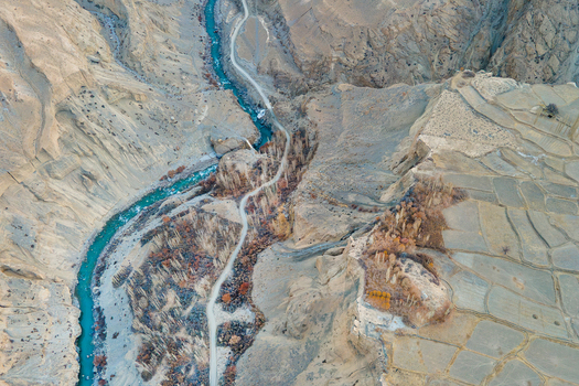 Aerial view of the turquoise river winding through the rugged arid landscape and terraced fields of Chapursan Valley Hunza Nagar Pakistan. Aerial view of the turquoise river winding through the rugged arid landscape and terraced fields of Chapursan Valley Hunza Nagar Pakistan.