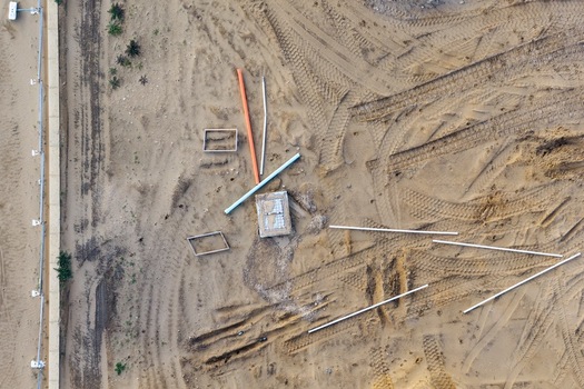 Aerial view of a residential development site featuring exposed sandy ground scattered construction pipes and vehicle tire tracks in Perth Western Australia Australia. Aerial view of a residential development site featuring exposed sandy ground scattered construction pipes and vehicle tire tracks in Perth Western Australia Australia.