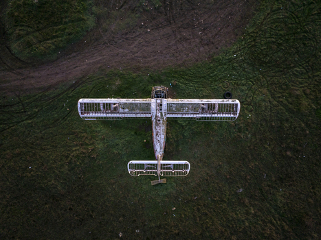 Aerial view of an abandoned skeletal biplane resting in a grassy field in Bulgaria. Aerial view of an abandoned skeletal biplane resting in a grassy field in Bulgaria.