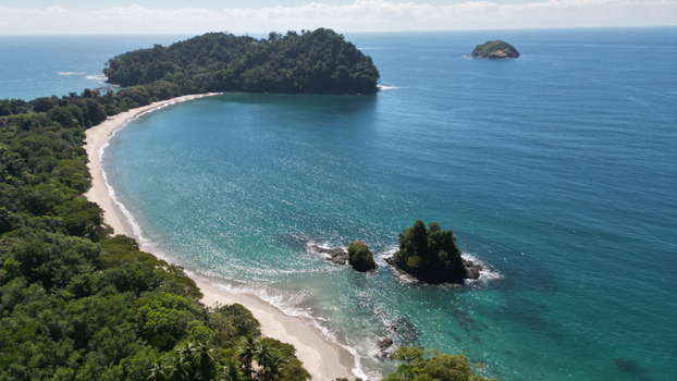 Aerial view of turquoise waters meet lush rainforest along the coast where small islands dot the horizon Quepos Puntarenas Province Costa Rica. Aerial view of turquoise waters meet lush rainforest along the coast where small islands dot the horizon Quepos Puntarenas Province Costa Rica.