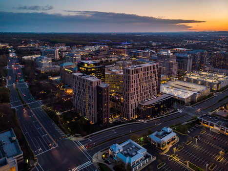 Reston United States 12 April 2020 Aerial view of the modern office buildings and urban landscape of Reston at sunset featuring illuminated skyscrapers and roads.