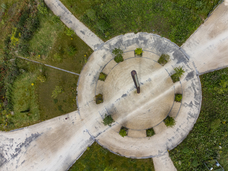 Aerial view of a concrete structure with radial pathways amidst the sprawling greenery a stark contrast in textures and tones Utopia Flevoland Netherlands.