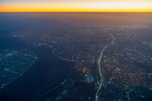 Aerial view of the sprawling city lights of Karachi at night with a vibrant twilight horizon illuminating the urban landscape of Karachi Sindh Pakistan.