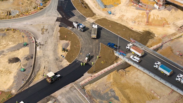 Aerial view of Black Cat Roundabout highway construction with heavy machinery asphalt paving and trucks on a bridge in Chawston England United Kingdom. Aerial view of Black Cat Roundabout highway construction with heavy machinery asphalt paving and trucks on a bridge in Chawston England United Kingdom.