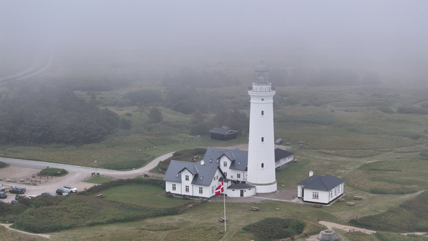 Aerial view of Hirtshals Fyr surrounded by green coastal landscape and fog in Hirtshals Denmark. Aerial view of Hirtshals Fyr surrounded by green coastal landscape and fog in Hirtshals Denmark.
