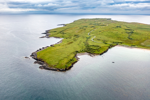 Aerial view of St John s Point Beach featuring a winding road along the grassy peninsula rugged coastline and clear Atlantic waters in Dunkineely County Donegal Ireland.