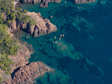 Aerial view of Le Trayas with kayakers paddling through the turquoise waters along the rugged red rock coastline in Saint Raphael Provence Alpes Cote d Azur France. Aerial view of Le Trayas with kayakers paddling through the turquoise waters along the rugged red rock coastline in Saint Raphael Provence Alpes Cote d Azur France.