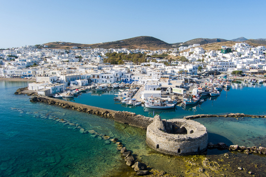 Naoussa Greece 21 September 2026 Aerial view of the historic Venetian fortress ruins in the harbor of Naoussa surrounded by traditional white buildings fishing boats and clear turquoise waters. Naoussa Greece 21 September 2026 Aerial view of the historic Venetian fortress ruins in the harbor of Naoussa surrounded by traditional white buildings fishing boats and clear turquoise waters.