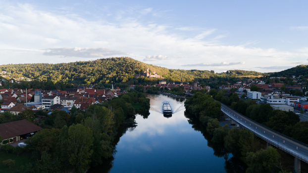 Aerial view of Wertheim Castle overlooking the Main river with a cargo ship historic town buildings and lush hills in Wertheim Baden Wurttemberg Germany. Aerial view of Wertheim Castle overlooking the Main river with a cargo ship historic town buildings and lush hills in Wertheim Baden Wurttemberg Germany.