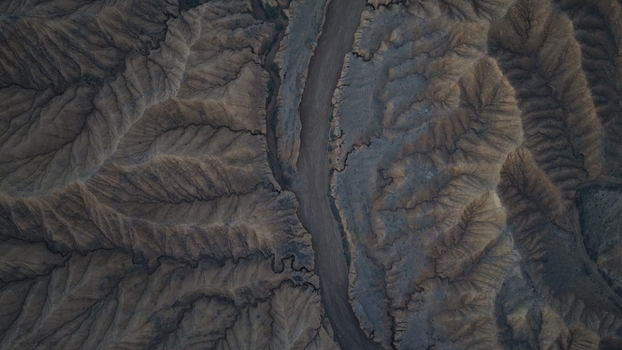 Aerial view of the rugged eroded landscape near Issyk Kul featuring deep canyons intricate ridges and dramatic shadows cast across the arid terrain in Issyk Kul Region Kyrgyzstan. Aerial view of the rugged eroded landscape near Issyk Kul featuring deep canyons intricate ridges and dramatic shadows cast across the arid terrain in Issyk Kul Region Kyrgyzstan.