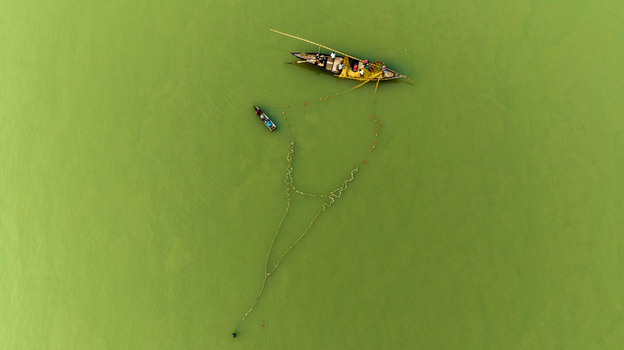 Aerial view of local fishermen working with traditional wooden boats and fishing nets on the river in Pabna Rajshahi Division Bangladesh.