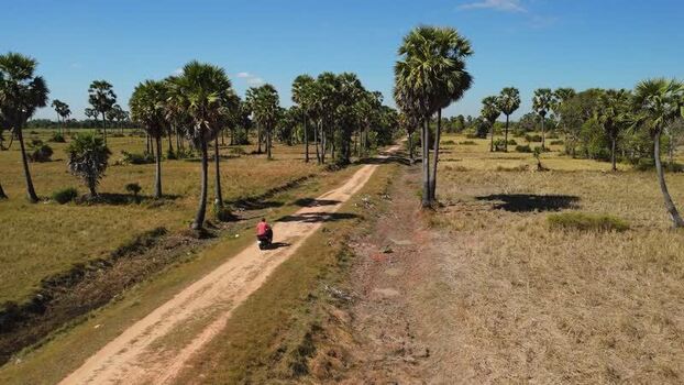 Aerial view of a motorbike on a rural dirt road in Cambodia. Aerial view of a motorbike on a rural dirt road in Cambodia.