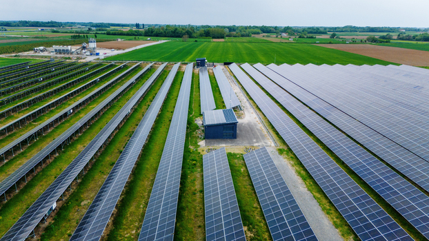 Aerial view of a large solar panel farm with rows of photovoltaic modules surrounded by green fields and rural landscape Sabac Vojvodina Serbia.