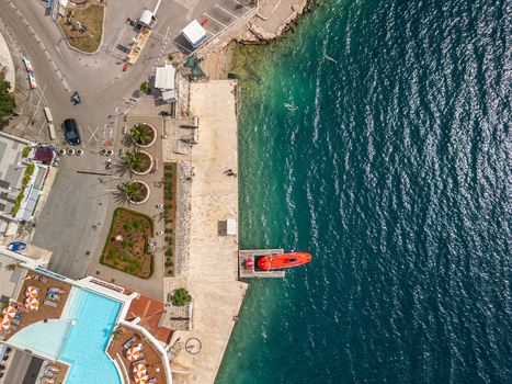 Neum Bosnia and Herzegovina 28 May 2025 Aerial view of Hotel Sunce Neum featuring a swimming pool a concrete pier with a red boat and the clear blue waters of the Adriatic Sea.