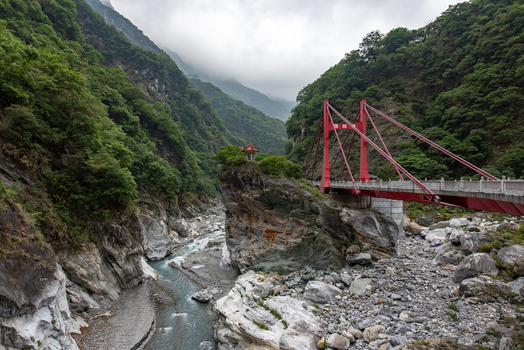 View of the red Changchun Bridge spanning the rocky gorge in Taroko National Park with the Changchun Shrine perched on a cliffside Xiulin Township Hualien County Taiwan.