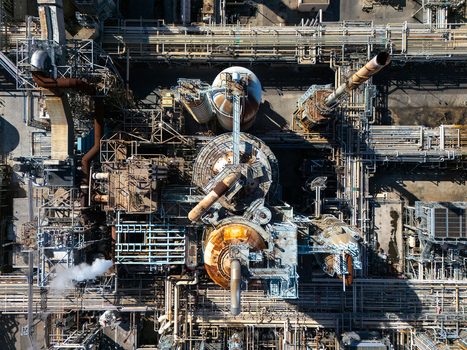 Aerial view of an industrial oil refinery complex featuring complex pipe networks large storage tanks and steel structures in Carson California United States.