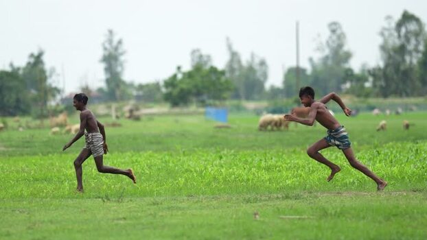 View of boys running in a green field in Bogura Bangladesh. View of boys running in a green field in Bogura Bangladesh.