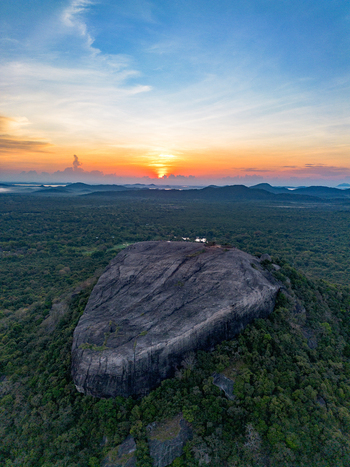 Aerial view of Pidurangala Rock surrounded by lush jungle foliage under a vibrant sunset sky in Sigiriya Central Province Sri Lanka. Aerial view of Pidurangala Rock surrounded by lush jungle foliage under a vibrant sunset sky in Sigiriya Central Province Sri Lanka.