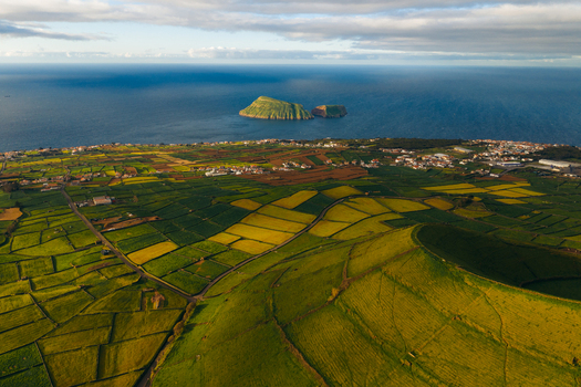 Aerial view of Pico Dona Joana geodesico overlooking the lush green patchwork fields and the Atlantic coastline in Feteira Acores Portugal. Aerial view of Pico Dona Joana geodesico overlooking the lush green patchwork fields and the Atlantic coastline in Feteira Acores Portugal.