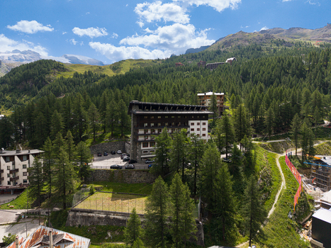 Aerial view of a large hotel nestled among dense pine forests and mountain slopes in Breuil Cervinia Aosta Valley Italy. Aerial view of a large hotel nestled among dense pine forests and mountain slopes in Breuil Cervinia Aosta Valley Italy.