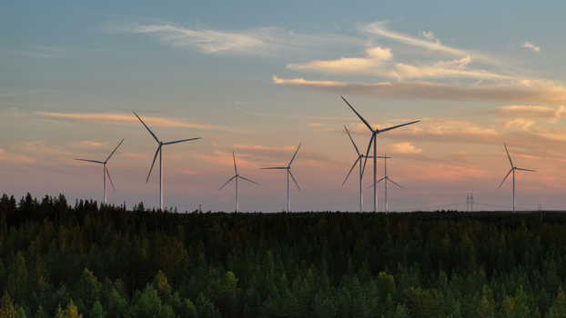 Aerial view of Metsalamminkangas Tuulipuisto wind farm with turbines rising above a dense forest under a golden hour sky in Siikalatva Pohjois Pohjanmaa Finland. Aerial view of Metsalamminkangas Tuulipuisto wind farm with turbines rising above a dense forest under a golden hour sky in Siikalatva Pohjois Pohjanmaa Finland.