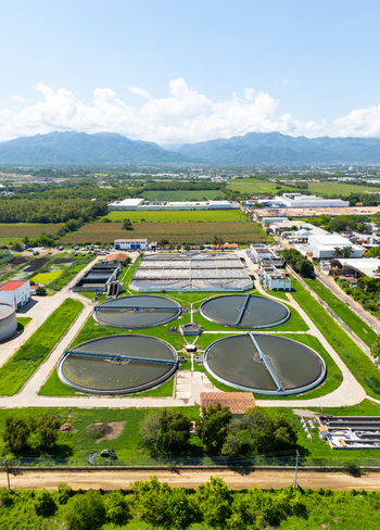 Aerial view of circular water treatment tanks amidst verdant fields and distant mountains a stark contrast of industry and nature Puerto Vallarta Mexico. Aerial view of circular water treatment tanks amidst verdant fields and distant mountains a stark contrast of industry and nature Puerto Vallarta Mexico.