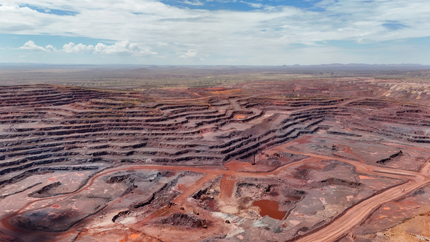 Aerial view of the colossal terraced open pit mine revealing a stark landscape of deep red earth under a vast partly cloudy sky Rustenburg North West South Africa. Aerial view of the colossal terraced open pit mine revealing a stark landscape of deep red earth under a vast partly cloudy sky Rustenburg North West South Africa.