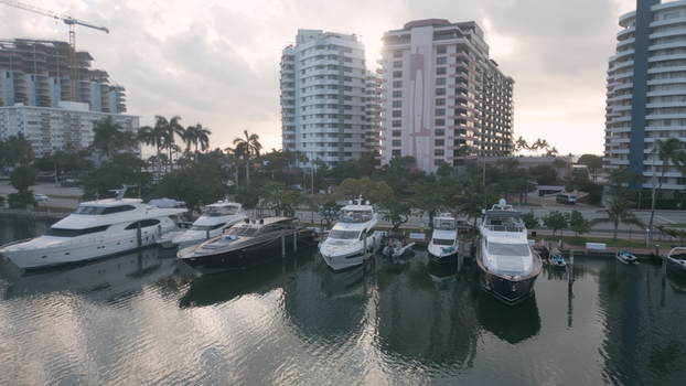 Aerial view of luxury yachts docked at a marina in Miami Beach with tall residential buildings and palm trees in the background Miami Beach Florida United States. Aerial view of luxury yachts docked at a marina in Miami Beach with tall residential buildings and palm trees in the background Miami Beach Florida United States.