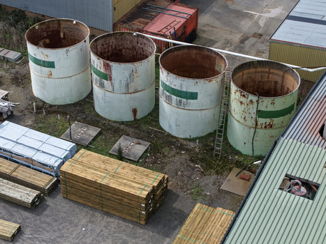 Melbourne Australia 25 September 2026 Aerial view of industrial site featuring large cylindrical storage tanks stacks of timber lumber and factory buildings.