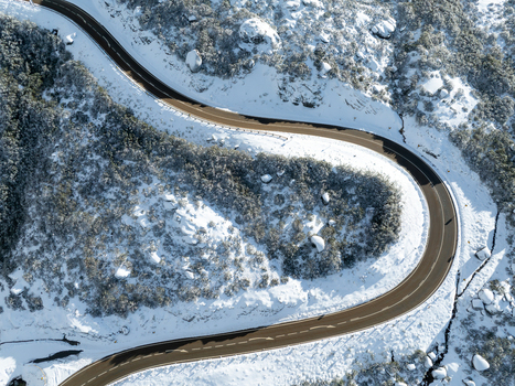 Aerial view of a winding road cuts through a snow laden landscape a ribbon of asphalt amidst the stark white wilderness São Romão Guarda District Portugal. Aerial view of a winding road cuts through a snow laden landscape a ribbon of asphalt amidst the stark white wilderness São Romão Guarda District Portugal.