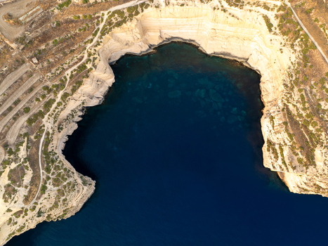 Aerial view of the rugged Sanap Cliffs meeting the deep blue sea where the sun kisses the pale stone Munxar Gozo Malta. Aerial view of the rugged Sanap Cliffs meeting the deep blue sea where the sun kisses the pale stone Munxar Gozo Malta.