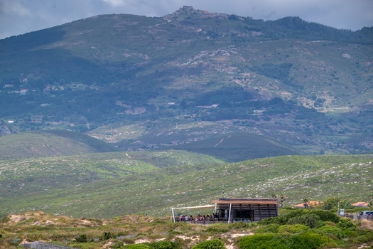 Cascais Lisbon Portugal 19 July 2026 View of the Nucleo de Interpretacao da Duna da Cresmina nestled in the coastal landscape with rolling green hills and a mountain backdrop. Cascais Lisbon Portugal 19 July 2026 View of the Nucleo de Interpretacao da Duna da Cresmina nestled in the coastal landscape with rolling green hills and a mountain backdrop.