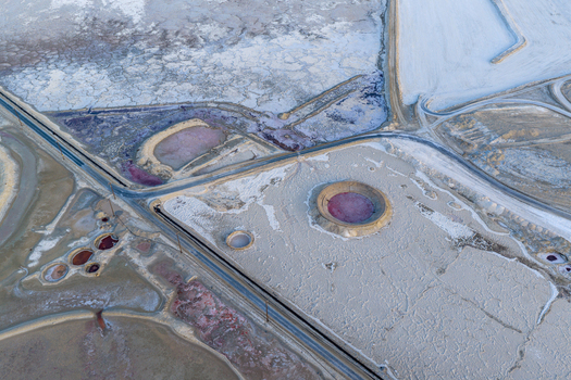 Aerial view of Searles Lake featuring pink brine pools white salt crust formations and circular evaporation ponds along industrial roads in San Bernardino County California United States. Aerial view of Searles Lake featuring pink brine pools white salt crust formations and circular evaporation ponds along industrial roads in San Bernardino County California United States.