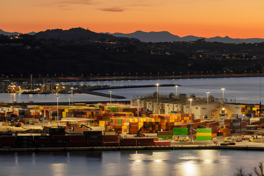 Aerial view of Ancona Port at sunset featuring colorful shipping containers industrial infrastructure and calm waters under a vibrant orange sky in Ancona Marche Italy. Aerial view of Ancona Port at sunset featuring colorful shipping containers industrial infrastructure and calm waters under a vibrant orange sky in Ancona Marche Italy.