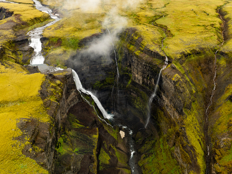 Aerial view of Haifoss waterfall plunging into a deep canyon surrounded by vibrant green mossy cliffs and rocky terrain in Skeida og Gnupverjahreppur Iceland. Aerial view of Haifoss waterfall plunging into a deep canyon surrounded by vibrant green mossy cliffs and rocky terrain in Skeida og Gnupverjahreppur Iceland.