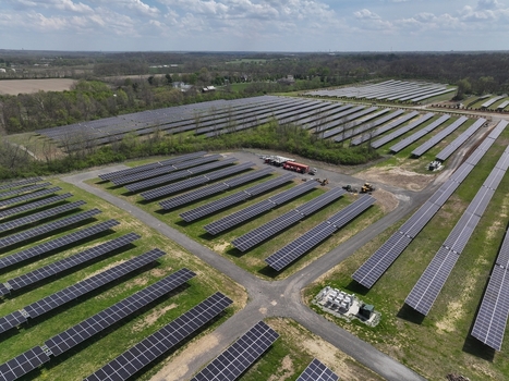 Lebanon United States 12 April 2026 Aerial view of a large solar farm with rows of photovoltaic panels installed on green fields surrounded by dense trees under a cloudy sky.