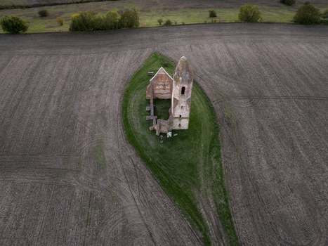 Aerial view of the historic Pusztatorony ruined church tower standing on a grassy island amidst vast plowed agricultural fields in Somogyvamos Hungary. Aerial view of the historic Pusztatorony ruined church tower standing on a grassy island amidst vast plowed agricultural fields in Somogyvamos Hungary.