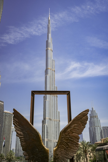 Dubai Dubai United Arab Emirates 24 April 2023 View of the Burj Khalifa framed by a metallic wing sculpture in the foreground under a clear blue sky. Dubai Dubai United Arab Emirates 24 April 2023 View of the Burj Khalifa framed by a metallic wing sculpture in the foreground under a clear blue sky.