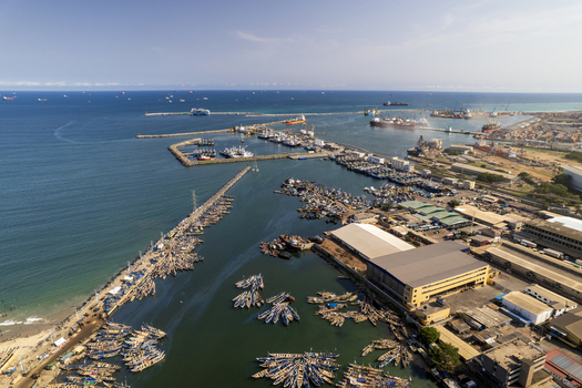 Aerial view of fishing boats clustered in the harbor contrasting with the vast deep blue sea stretching to the horizon Tema Ghana. Aerial view of fishing boats clustered in the harbor contrasting with the vast deep blue sea stretching to the horizon Tema Ghana.