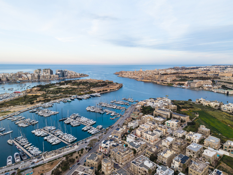 Aerial view of the Msida Marina with numerous yachts and sailboats moored near historic stone buildings and urban coastal developments in Malta. Aerial view of the Msida Marina with numerous yachts and sailboats moored near historic stone buildings and urban coastal developments in Malta.