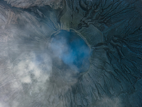 Aerial view of the crater of Mount Bromo with volcanic ash rugged textures and swirling smoke in Kecamatan Kademangan Jawa Timur Indonesia.