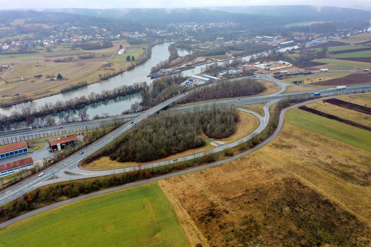 Aerial view of the Main Donau Kanal and a highway interchange surrounded by green fields and the town of Forchheim Bavaria Germany.