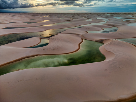 Aerial view of Lagoa Bonita with its emerald green lagoons nestled among vast white sand dunes under a dramatic sunset sky in Barreirinhas Maranhao Brazil. Aerial view of Lagoa Bonita with its emerald green lagoons nestled among vast white sand dunes under a dramatic sunset sky in Barreirinhas Maranhao Brazil.