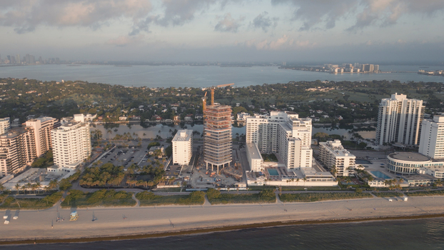 Aerial view of the Miami Beach coastline featuring high rise residential buildings a construction site with a crane sandy beach and ocean waters in Miami Beach Florida United States. Aerial view of the Miami Beach coastline featuring high rise residential buildings a construction site with a crane sandy beach and ocean waters in Miami Beach Florida United States.
