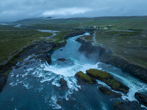 Aerial view of Godafoss Waterfall with its powerful cascading water flowing through a rugged rocky landscape under a cloudy sky in Thingeyjarsveit Iceland. Aerial view of Godafoss Waterfall with its powerful cascading water flowing through a rugged rocky landscape under a cloudy sky in Thingeyjarsveit Iceland.