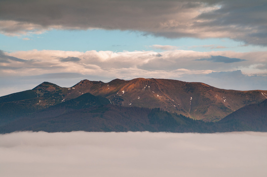 Aerial view of Mala Fatra mountain ridge rising above a sea of clouds during golden hour in Turany Zilina Region Slovakia.