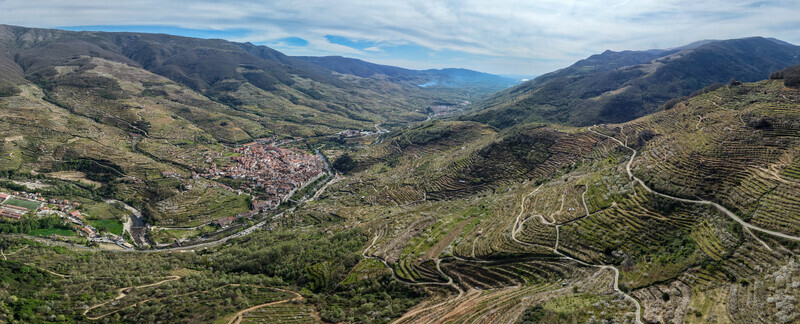 Aerial view of the sun drenched village nestled between terraced hills and lush mountains Cabezuela del Valle Extremadura Spain.