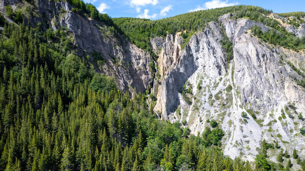 Aerial view of a waterfall cascading down steep rocky cliffs surrounded by dense evergreen forests in the mountainous landscape of Coyhaique Aysen Chile. Aerial view of a waterfall cascading down steep rocky cliffs surrounded by dense evergreen forests in the mountainous landscape of Coyhaique Aysen Chile.