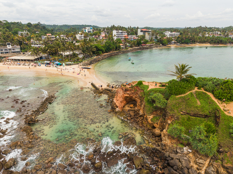 Aerial view of Parrot Rock and the sandy beach with turquoise water and lush palm trees in Mirissa Southern Province Sri Lanka. Aerial view of Parrot Rock and the sandy beach with turquoise water and lush palm trees in Mirissa Southern Province Sri Lanka.